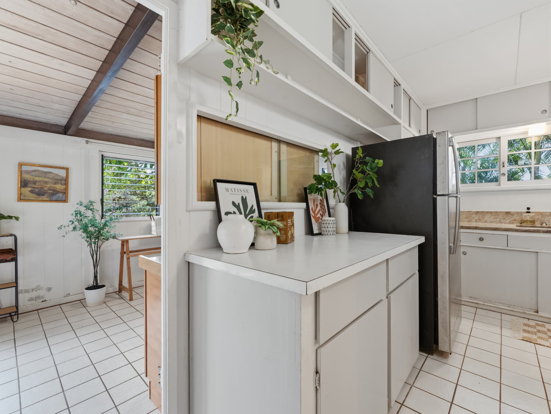 Kitchen pass-through counter with refrigerator and view to the adjacent room