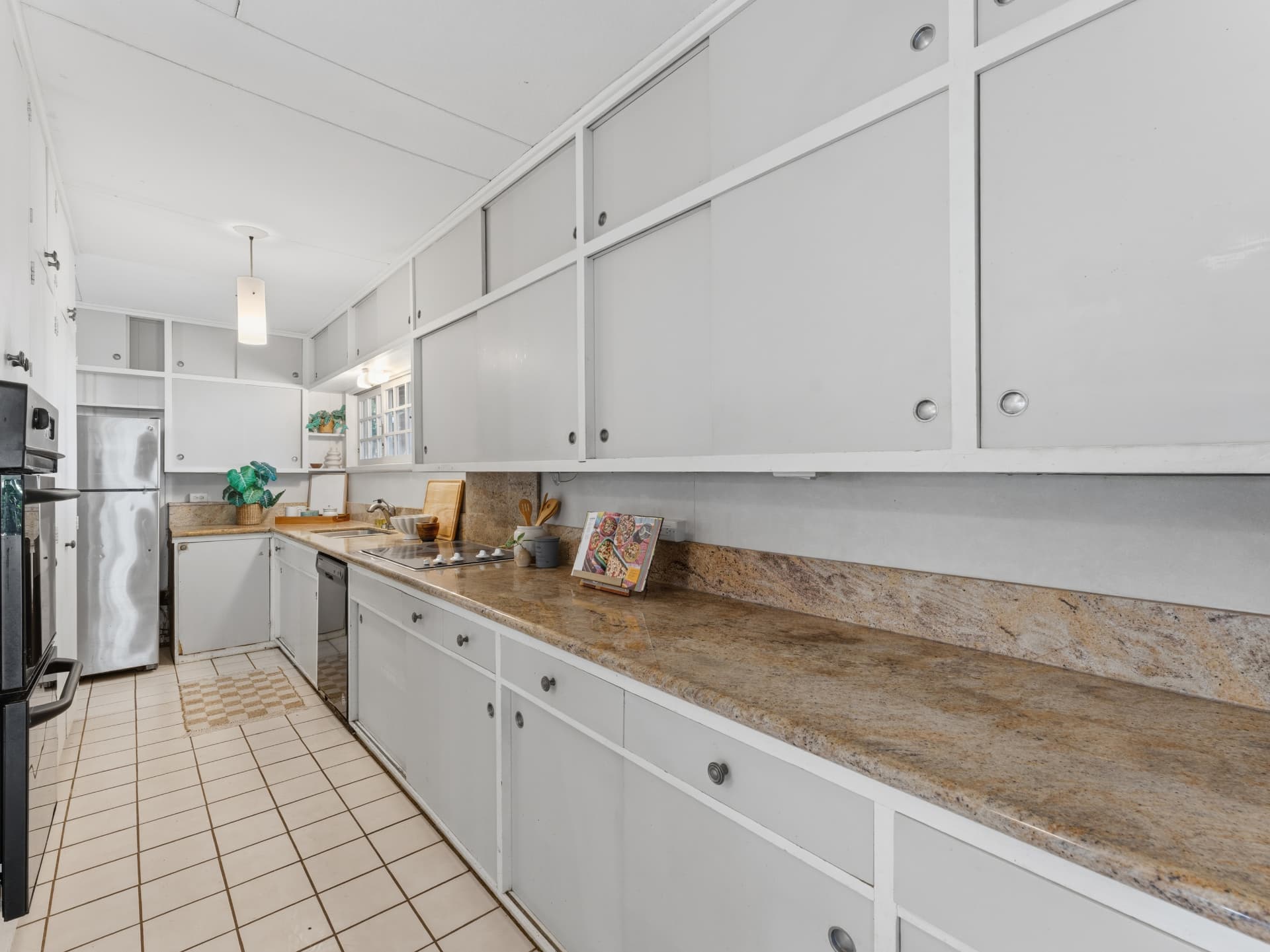 Galley kitchen with granite counters, backsplash, and full-length white cabinetry