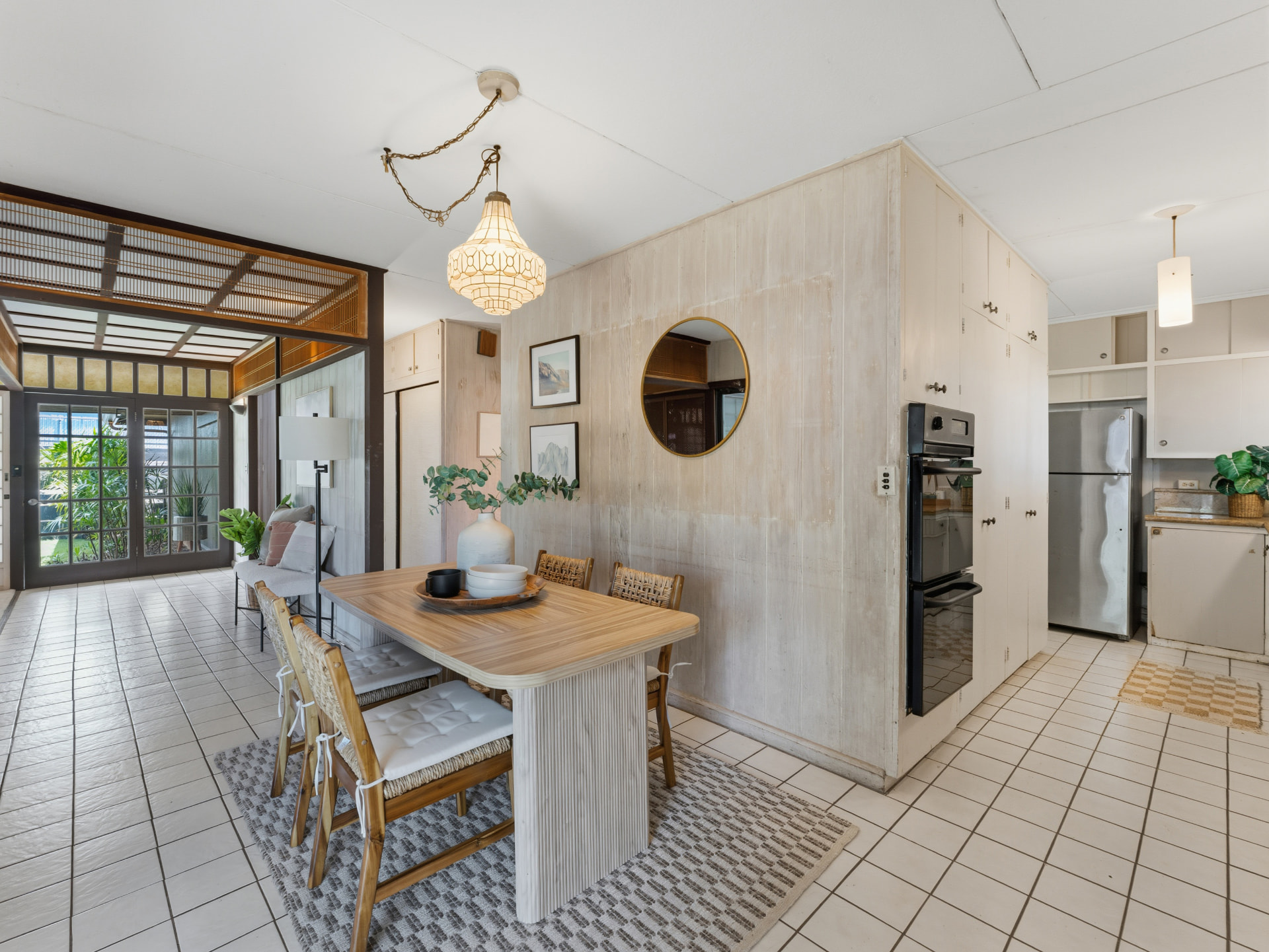 Dining area with pendant light, round mirror, and built-in cabinetry beside the kitchen